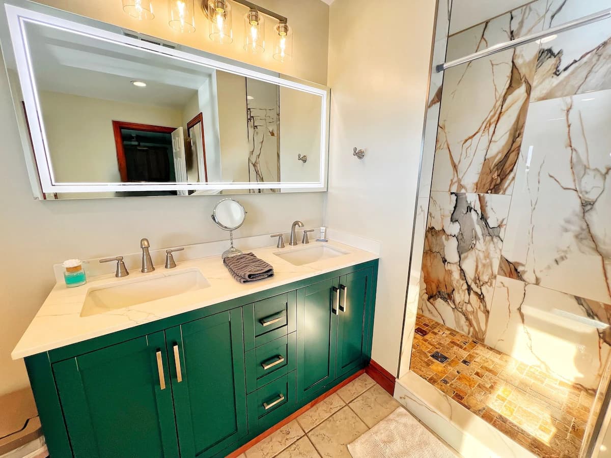 Modern bathroom with teal vanity and marble shower