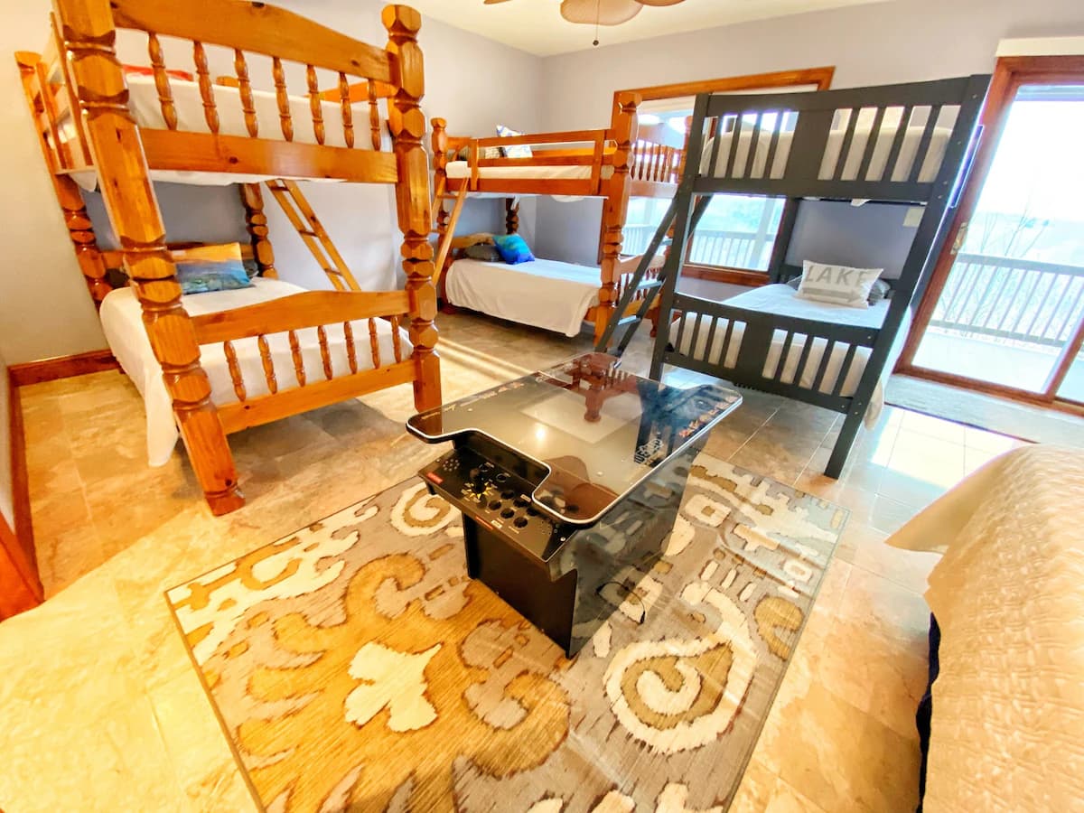 Bunk room with multiple beds and arcade table