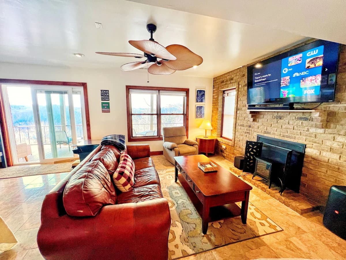 Spacious living room with leather sectional and stone fireplace